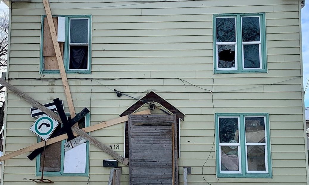 Boarded-up house in snowy Winnipeg, showing urban decay in winter.