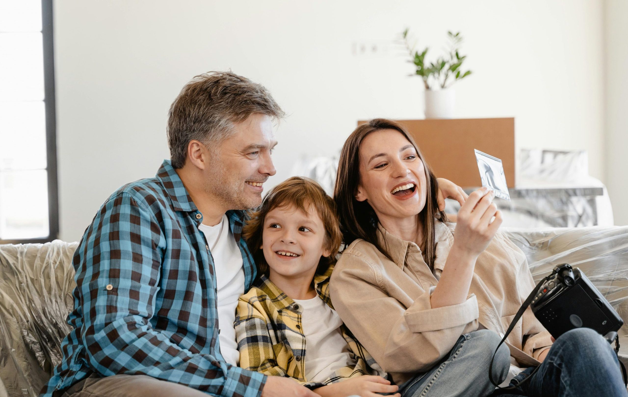 A cheerful family enjoys time together on a couch surrounded by moving boxes in their new home.